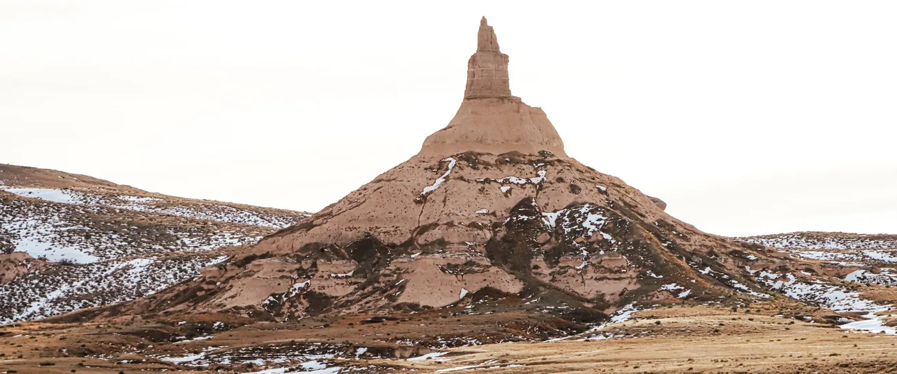 Sandstone landmark rising above snow-dusted prairie