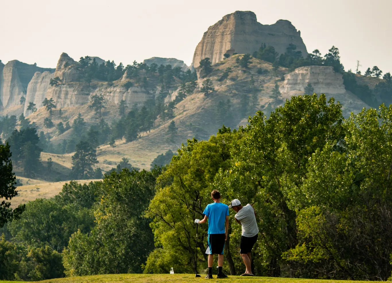 Two golfers beneath sandstone bluffs