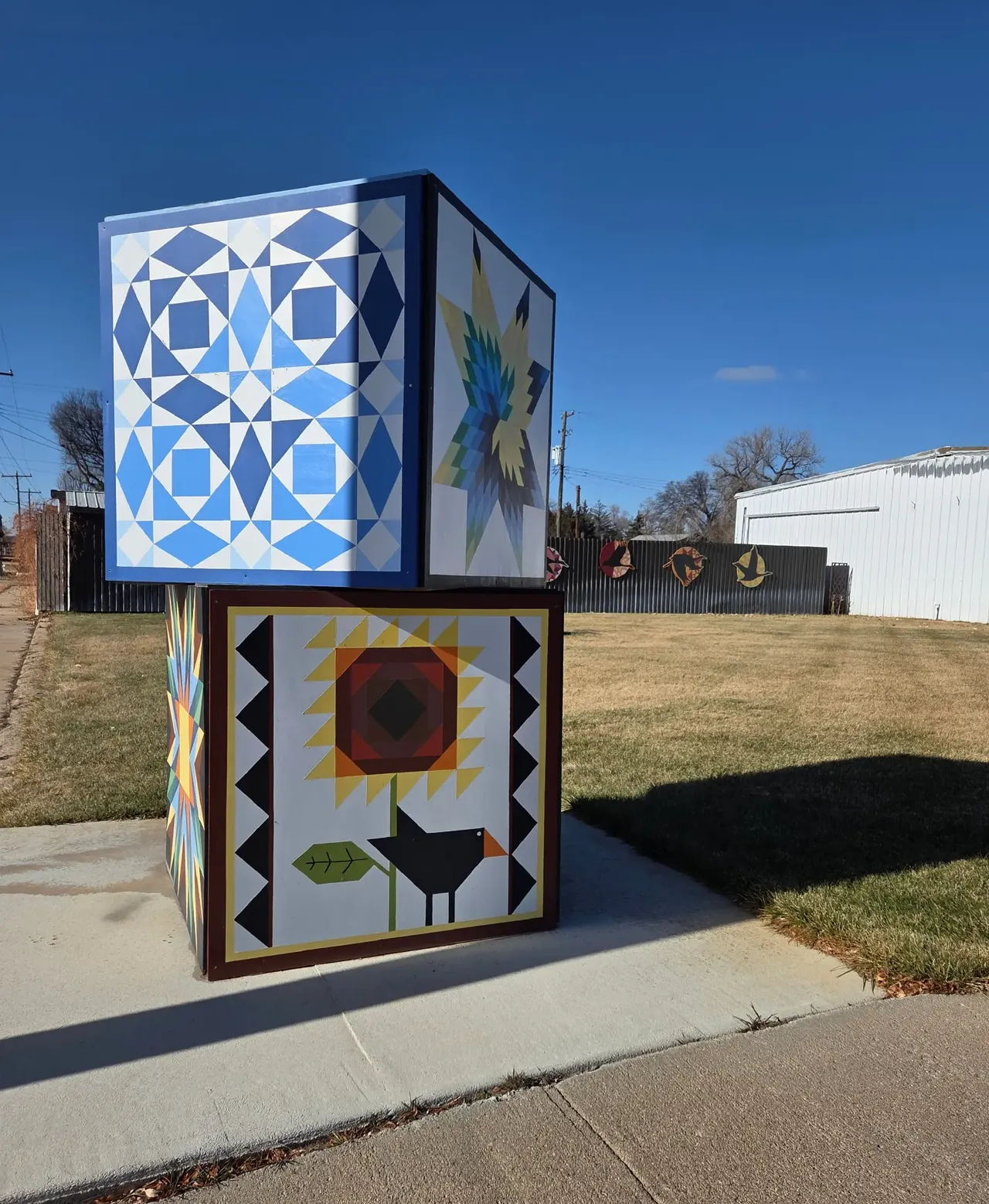 Painted quilt block sculpture beside a sidewalk