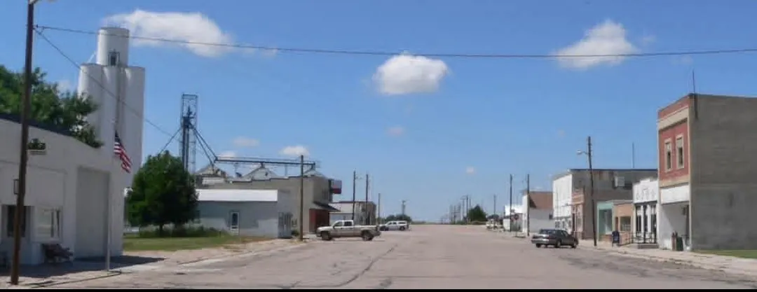 Small-town main street with storefronts and a grain elevator